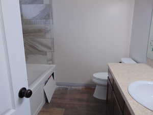 Bathroom featuring vanity, hardwood / wood-style flooring, toilet, and a washtub