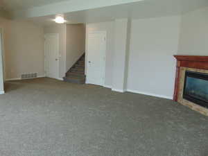 Unfurnished living room featuring dark colored carpet and a tiled fireplace