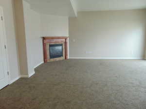 Unfurnished living room with carpet floors and a tile fireplace