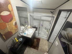 Bathroom featuring vanity, walk in shower, crown molding, tile patterned floors, and a textured ceiling