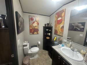 Bathroom with toilet, vaulted ceiling, a textured ceiling, vanity, and tile patterned flooring