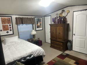 Bedroom with light colored carpet, vaulted ceiling, and a textured ceiling