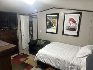 Bedroom featuring light carpet, vaulted ceiling, and a textured ceiling