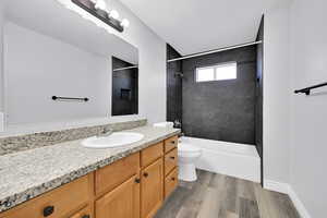 Full bathroom with vanity, toilet, tiled shower / bath combo, and wood-type flooring