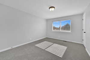 Unfurnished room featuring dark carpet