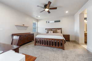 Bedroom featuring ceiling fan, connected bathroom, and light carpet