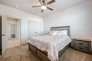 Bedroom featuring light carpet, ceiling fan, and a closet