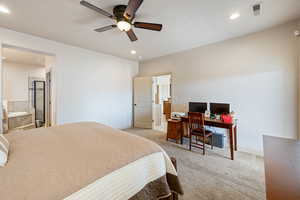 Bedroom with ceiling fan, ensuite bathroom, and light carpet