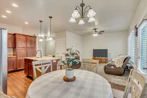 Dining area featuring wood-type flooring, sink, and ceiling fan with notable chandelier