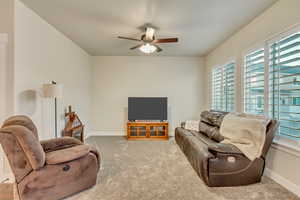 Carpeted living room with ceiling fan