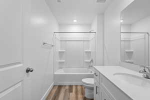 Full bathroom featuring hardwood / wood-style flooring, shower / bath combination, vanity, a textured ceiling, and toilet