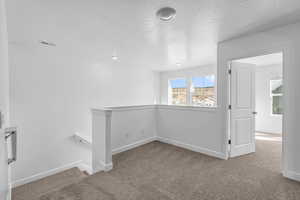 Carpeted spare room featuring a textured ceiling