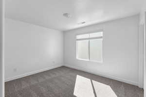 Spare room with a textured ceiling and dark colored carpet