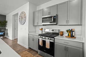 Kitchen featuring stainless steel appliances, dark hardwood / wood-style flooring, and gray cabinets