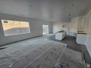 Kitchen with white cabinetry, a center island, sink, and a textured ceiling