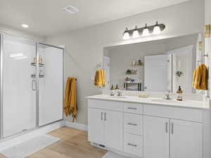 Bathroom with wood-type flooring, a shower with door, and vanity