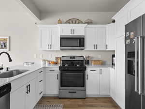 Kitchen with white cabinetry, appliances with stainless steel finishes, sink, and hardwood / wood-style floors