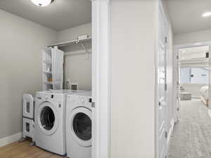 Washroom featuring separate washer and dryer, light colored carpet, and a textured ceiling