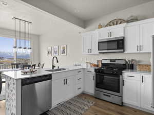 Kitchen with sink, stainless steel appliances, kitchen peninsula, and white cabinets