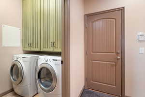 Washroom featuring washer and clothes dryer and cabinets