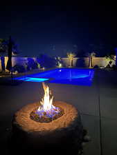 Pool at night featuring an outdoor fire pit