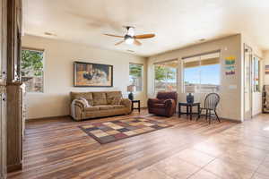 Living room with ceiling fan, light hardwood / wood-style flooring, and a textured ceiling