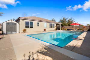 View of pool featuring a storage unit and a patio