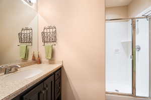 Bathroom featuring a shower with door and vanity