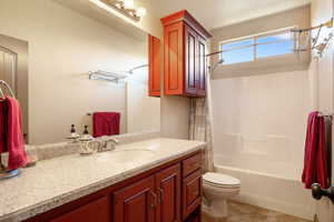 Full bathroom with shower / bath combo, vanity, tile patterned floors, and toilet