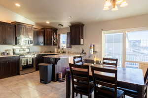 Dining rooms and kitchen with vaulted ceiling, dark brown cabinetry, stainless steel appliances, and light granite countertops