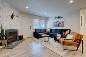 Living room featuring a stone fireplace, a textured ceiling, and light wood-type flooring