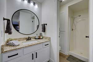 Bathroom featuring walk in shower, vanity, toilet, and hardwood / wood-style flooring