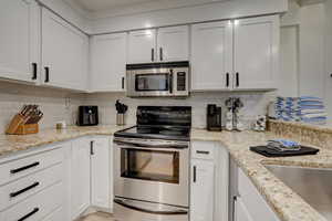 Kitchen with tasteful backsplash, stainless steel appliances, and white cabinets