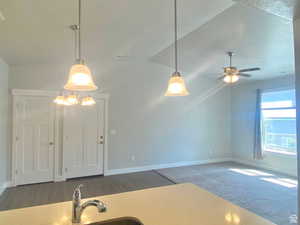 Kitchen featuring hanging light fixtures, dark carpet, sink, and ceiling fan