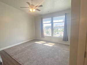 Carpeted spare room featuring ceiling fan and a textured ceiling