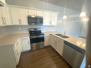 Kitchen featuring stainless steel appliances, sink, pendant lighting, and white cabinets