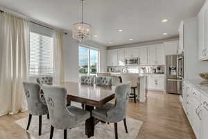 Dining room with a notable chandelier, a healthy amount of sunlight, and light wood-type flooring