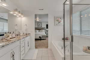 Bathroom with tile patterned flooring, vanity, and shower with separate bathtub