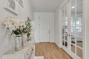 Doorway with light hardwood / wood-style floors and french doors