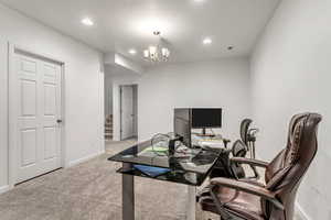 Office area with an inviting chandelier and light colored carpet