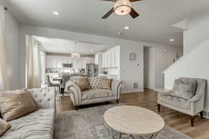 Living room featuring ceiling fan with notable chandelier, light hardwood / wood-style floors, and a textured ceiling