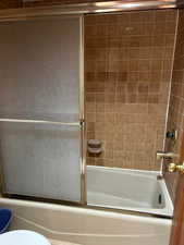 Bathroom featuring enclosed tub / shower combo and toilet