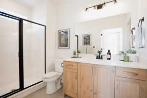 Bathroom with walk in shower, tile patterned floors, vanity, and toilet