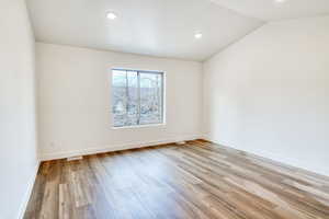 Spare room featuring vaulted ceiling and light hardwood / wood-style floors