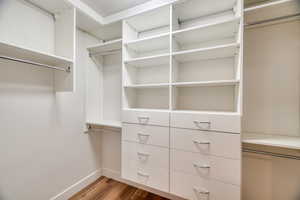 Walk in closet with hardwood / wood-style flooring