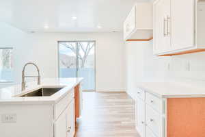 Kitchen with an island with sink, a wealth of natural light, sink, and white cabinets