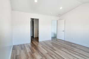 Unfurnished bedroom with hardwood / wood-style flooring and lofted ceiling