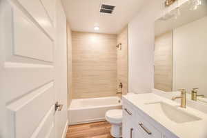 Full bathroom featuring vanity, toilet, tiled shower / bath combo, and hardwood / wood-style floors