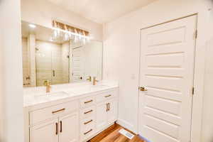 Bathroom with vanity, hardwood / wood-style floors, and a shower with door