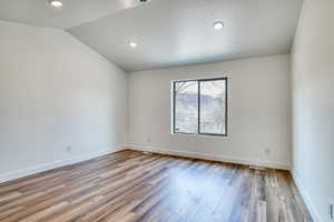 Empty room with wood-type flooring and lofted ceiling